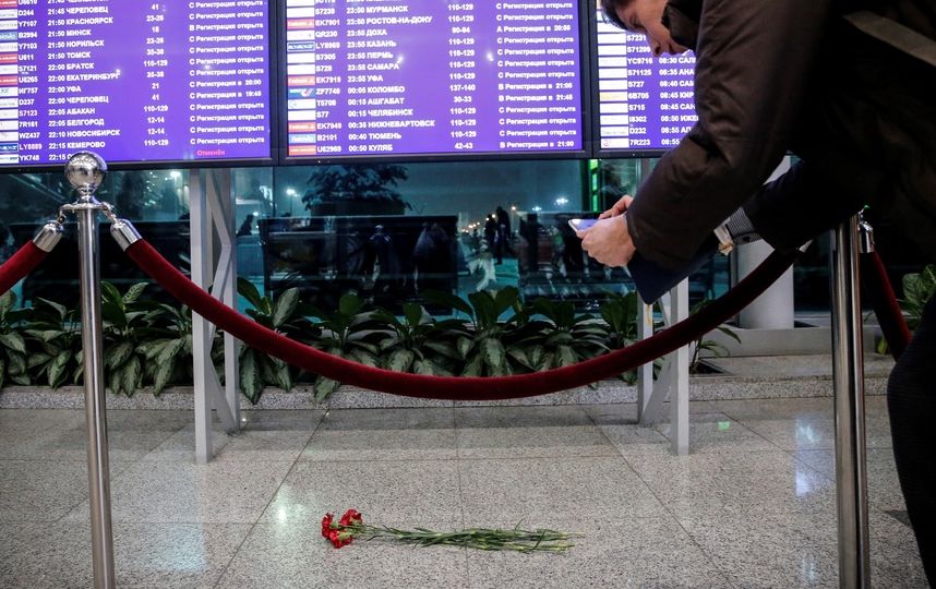 Люди оставляют цветы под расписанием полётов в столичном аэропорту Домодедово. Фото AFP