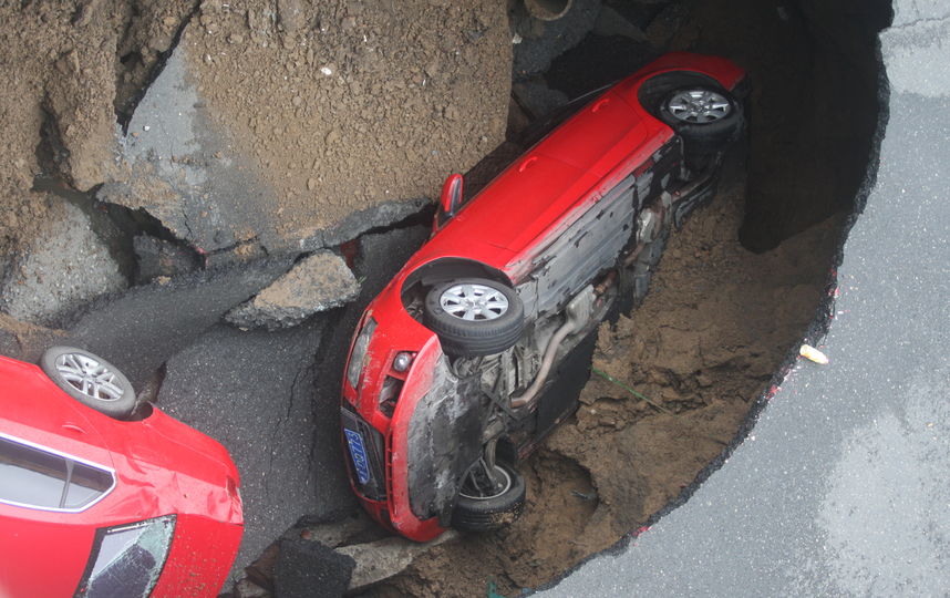Авто провалились в яму, размытую дождями. Фото Getty