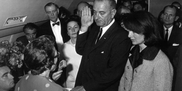 Джеки, в запачканном кровью розовом костюме, в то время как Джонсон даёт присягу при вступлении в должность президента.