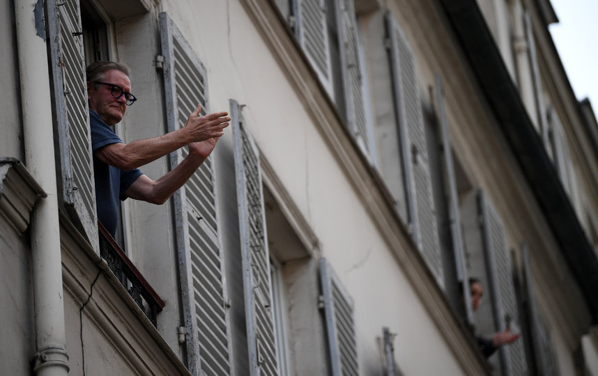 Житель Парижа аплодисментами благодарит врачей за работу из окна своей квартиры. В России такого пока наблюдать не приходится. Фото AFP