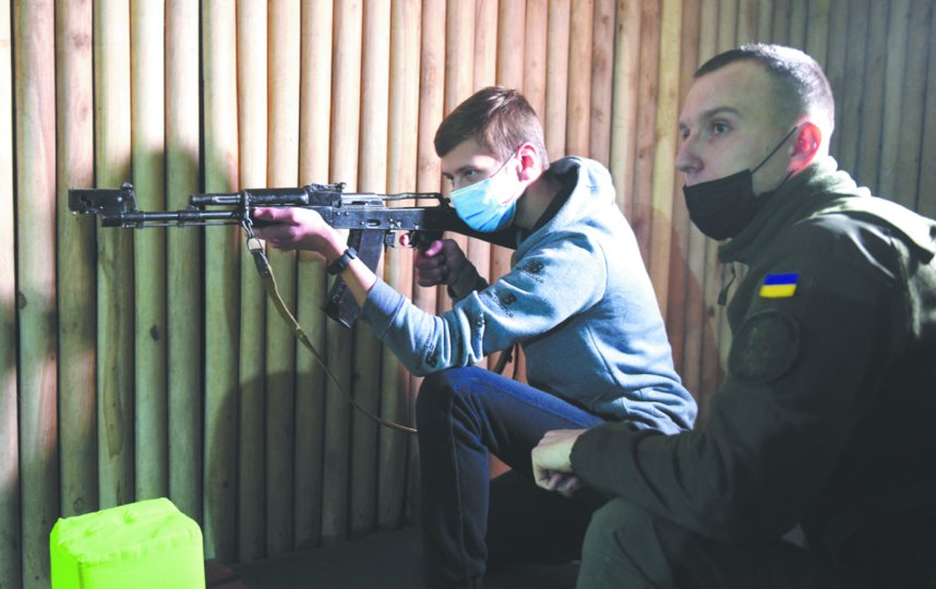 Военный инструктор обучает старшеклассника стрельбе из калашникова во Львове. Фото AFP