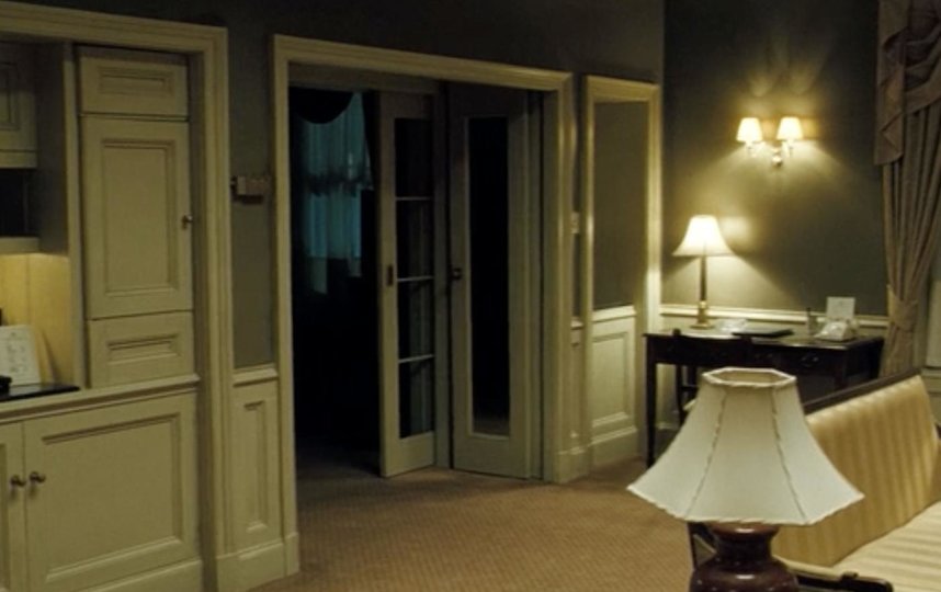 Гостиная номера 1408. На полу лежит ковёр, мебель – либо деревянная, либо обтянутая текстилем. Фото Кадр из фильма.