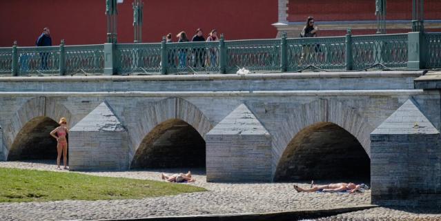 Петербуржцы принимают солнечные ванные у Петропавловской крепости.